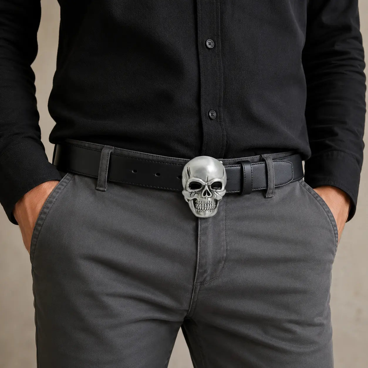 Man wearing a black shirt and gray pants with a skull belt buckle.