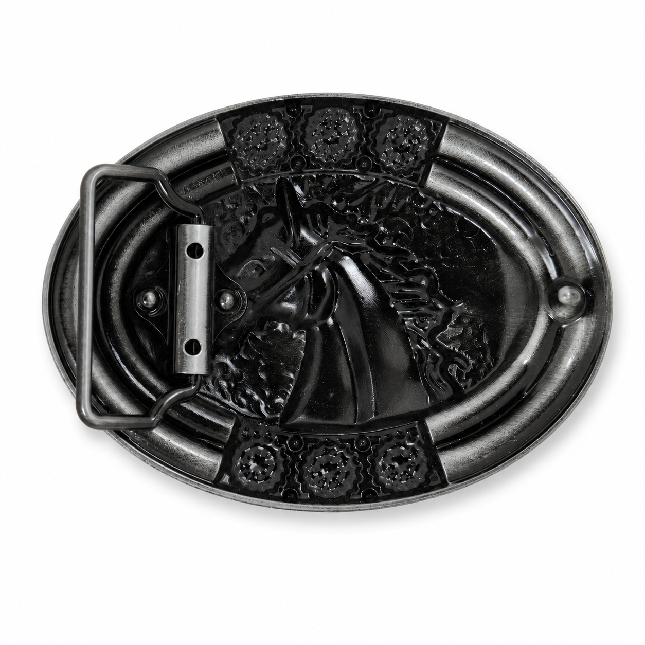 Rear of an oval black metal belt buckle featuring a raised embossed design of a horse head, with decorative floral details at the corners and a rectangular metal keeper loop on the left side, shown on a plain white background.