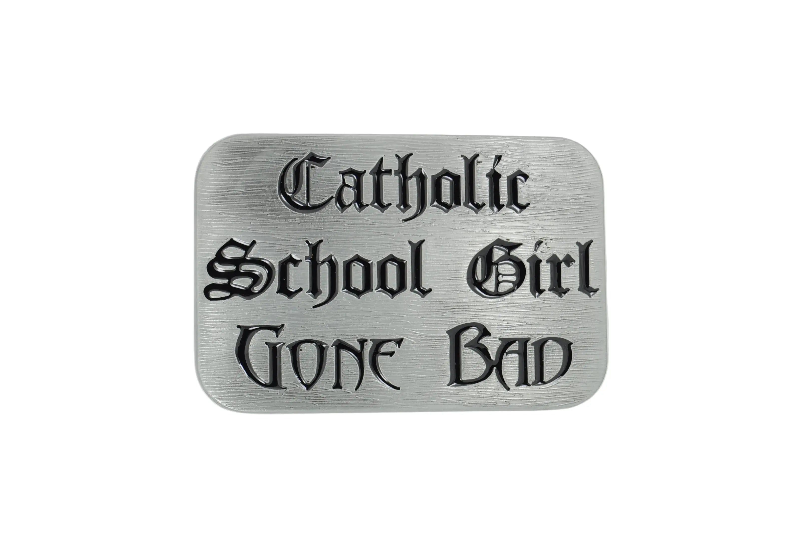 A rectangular silver metal belt buckle with rounded corners, featuring the text 'Catholic School Girl GONE BAD' in a black gothic font, set against a plain white background.