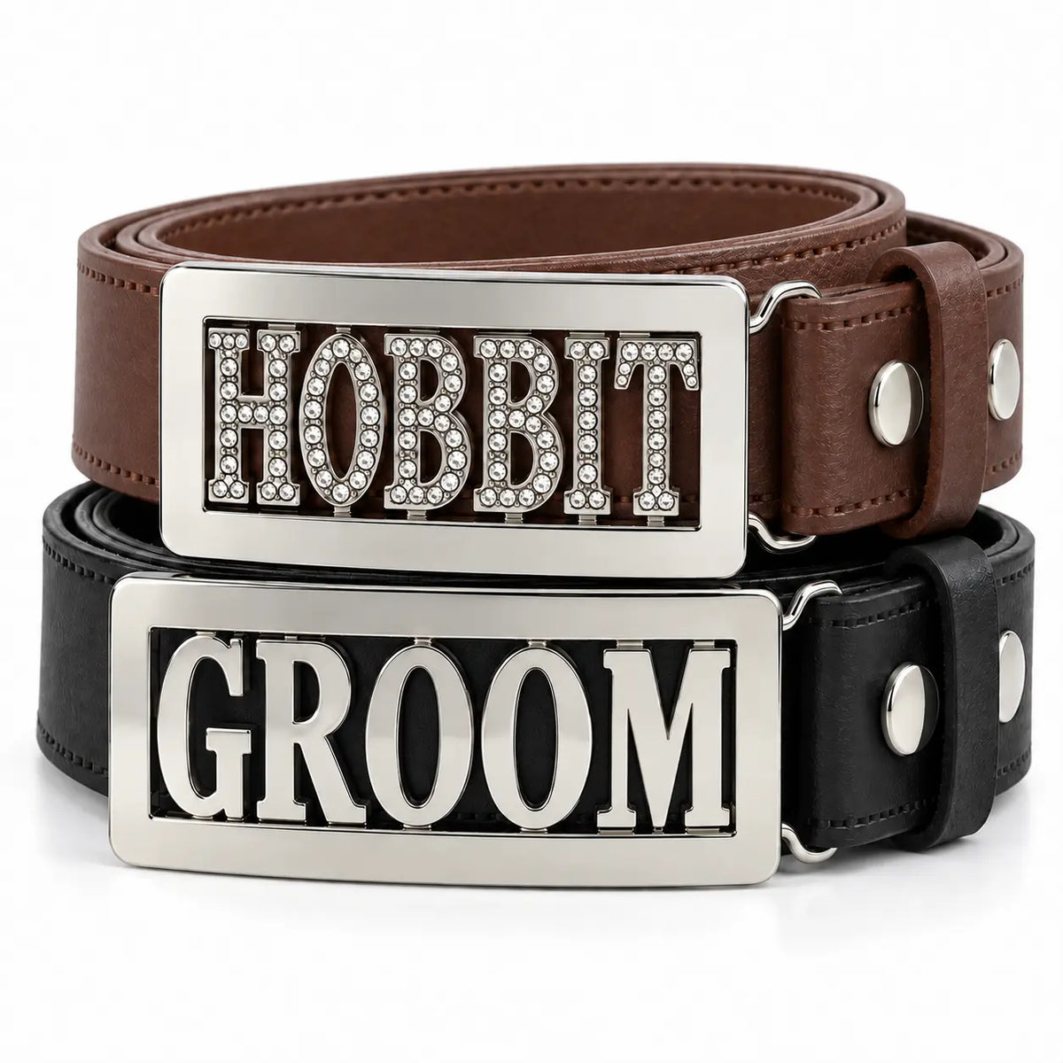 Two novelty personalised belt buckles stacked on a white background: a brown leather belt with a silver rectangular buckle spelling 'HOBBIT' in rhinestone letters, and a black leather belt with a matching silver buckle spelling 'GROOM'.