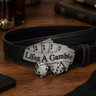 Black belt with a decorative buckle featuring playing card symbols and dice on a wooden surface.