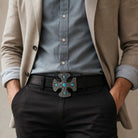Man wearing a beige blazer, blue shirt, black pants, and a belt with a decorative buckle.