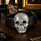 Skull-shaped belt buckle on a black leather belt with a blurred background