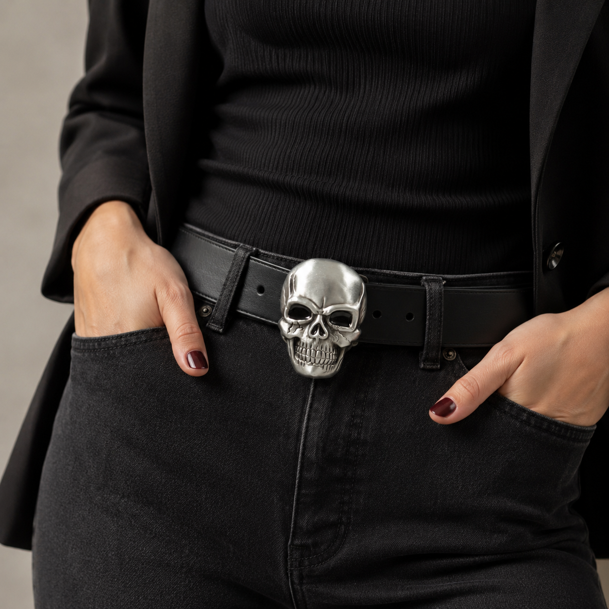 Lady wearing a black outfit with a skull belt buckle on a neutral background