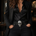 Lady wearing a black outfit with a skull belt buckle in a dimly lit setting