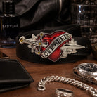 Belt buckle with 'LOVE HURTS' design on a wooden surface with accessories.
