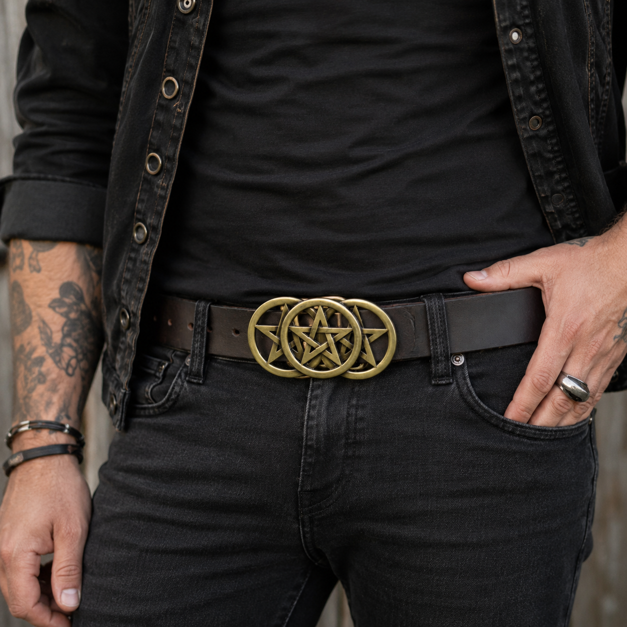 Man wearing a black shirt, black pants, and a belt with a gold pentagram buckle.