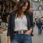 Woman in a white blouse and blue jeans standing in an outdoor market setting wearing a celtic cross belt buckle.