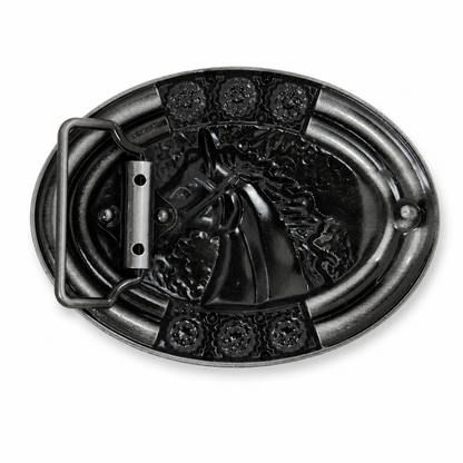 Rear of an oval black metal belt buckle featuring a raised embossed design of a horse head, with decorative floral details at the corners and a rectangular metal keeper loop on the left side, shown on a plain white background.