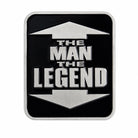 A rectangular black belt buckle with rounded corners, featuring a brushed silver metallic border and a matching silver arrow design pointing up and down, with the text 'THE MAN THE LEGEND' in silver block letters in the center.