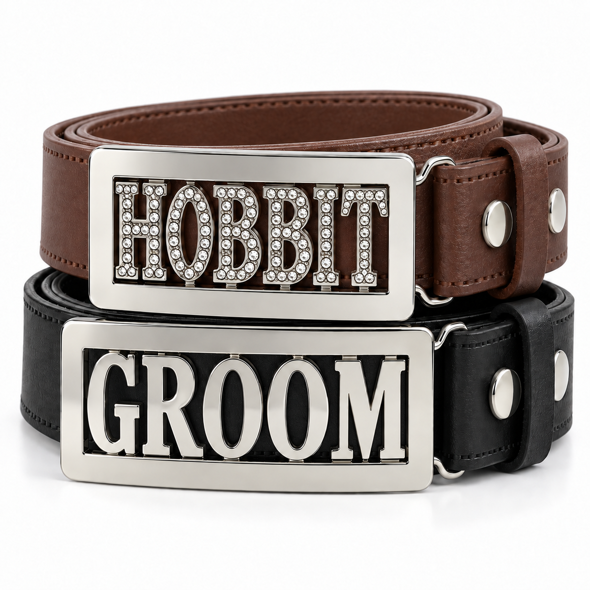 Two novelty personalised belt buckles stacked on a white background: a brown leather belt with a silver rectangular buckle spelling 'HOBBIT' in rhinestone letters, and a black leather belt with a matching silver buckle spelling 'GROOM'.