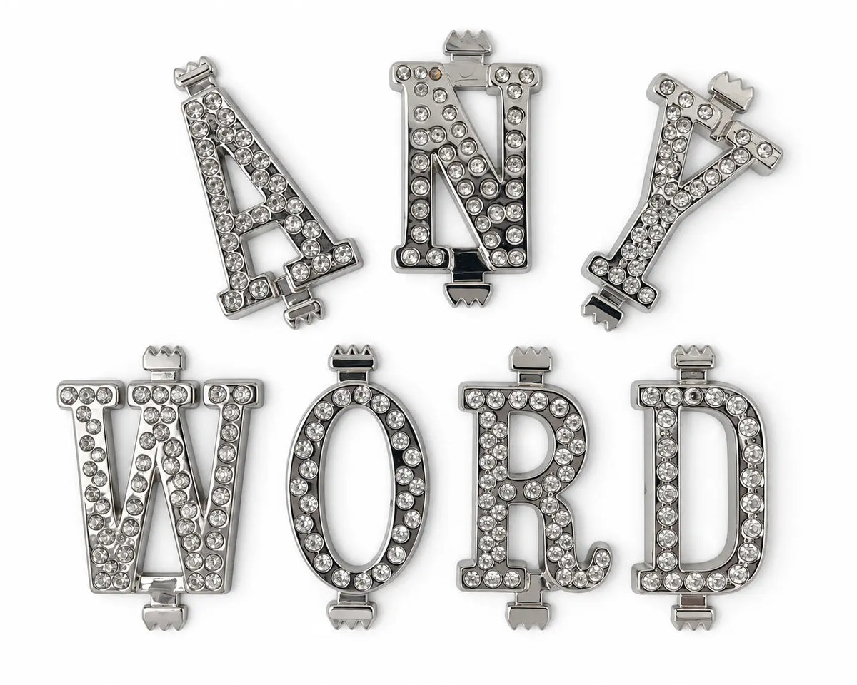A set of silver belt buckle letters with clear rhinestones, arranged on a plain white background. The set includes letters M, A, O, R, D, and Y in various font styles.