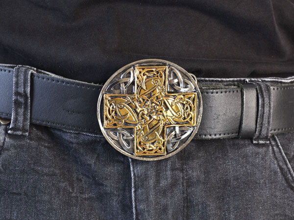 Close-up of a celtic cross buckle on dark jeans.